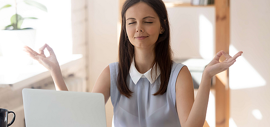 Junge Frau integriert Meditation gegen Stress am Arbeitsplatz