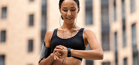 Eine Frau kontrolliert ihren Puls anhand einer Fitnessuhr beim Sport