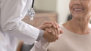 Ärztin unterhält sich bei einer älteren weiblichen Patientin.