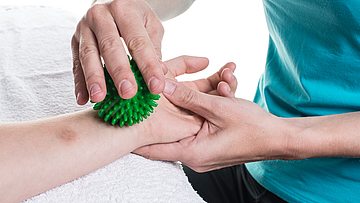 Therapeut behandelt den Arm eines Patienten mit einem Igelball.