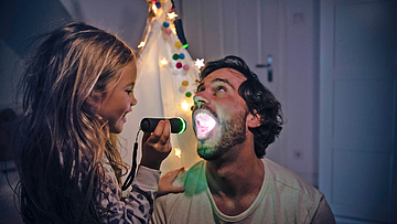 Kind untersucht Zähne des Vaters