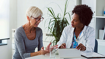 Eine Ärztin bespricht mit einer Patientin im Behandlungszimmer das Untersuchungsergebnis.