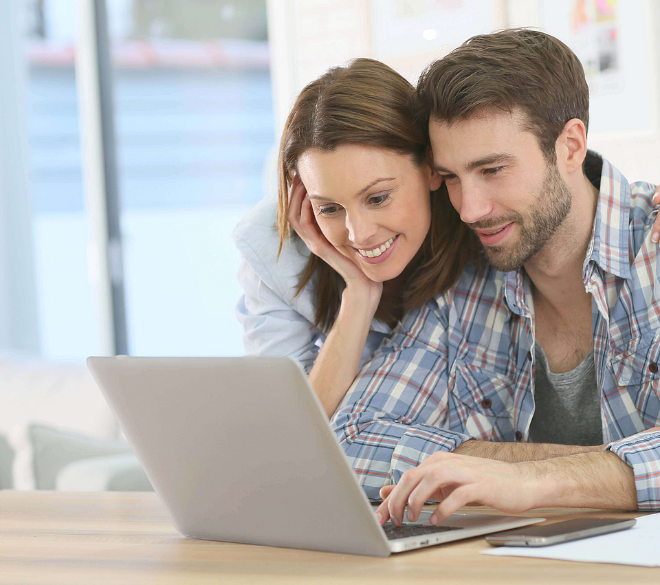 Ein junges Paar sitzt am Schreibtisch und rechnet mit dem Lohn- & Gehaltsrechner die Beiträge zur Krankenversicherung aus.