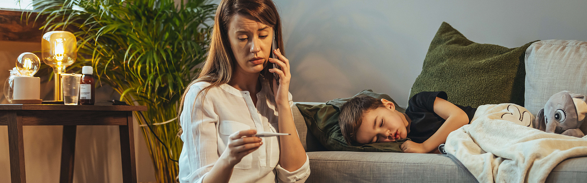 Schuss von einer Mutter, die zu Hause einen Anruf macht, während sie ihrem kranken jungen Sohn hilft. Mutter überprüft die Temperatur ihres kranken Sohnes. Nahaufnahme einer Mutter, die die Temperatur ihres Jungen überprüft.