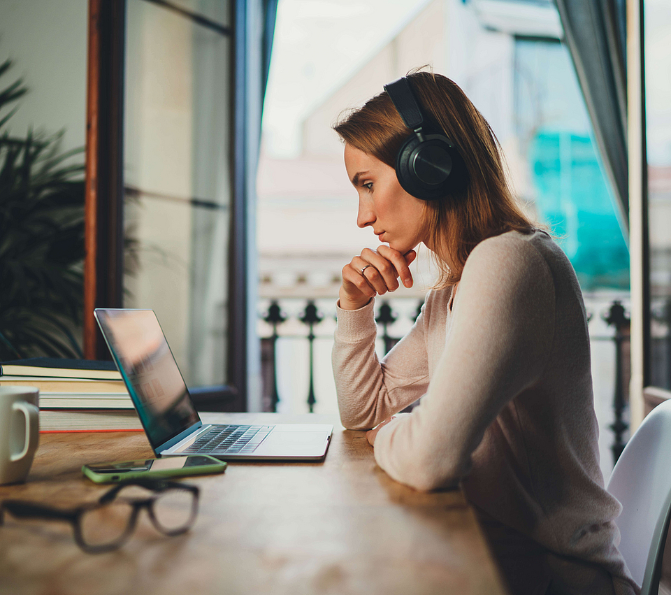 Zu sehen ist eine Frau, die mit dem Laptop arbeitet.