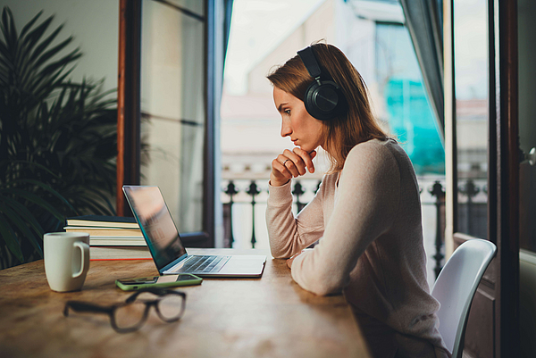 Zu sehen ist eine Frau, die mit dem Laptop arbeitet.