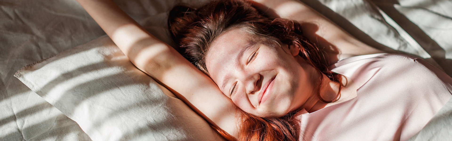 fröhliche Frau liegt im Bett und träumt vom Abnehmen im Schlaf