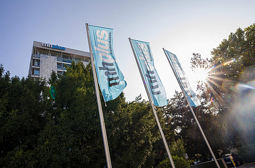 Das Bürogebäude und Hauptsitz der mhplus Krankenkasse in Ludwigsburg mit Flaggen und Bäumen davor