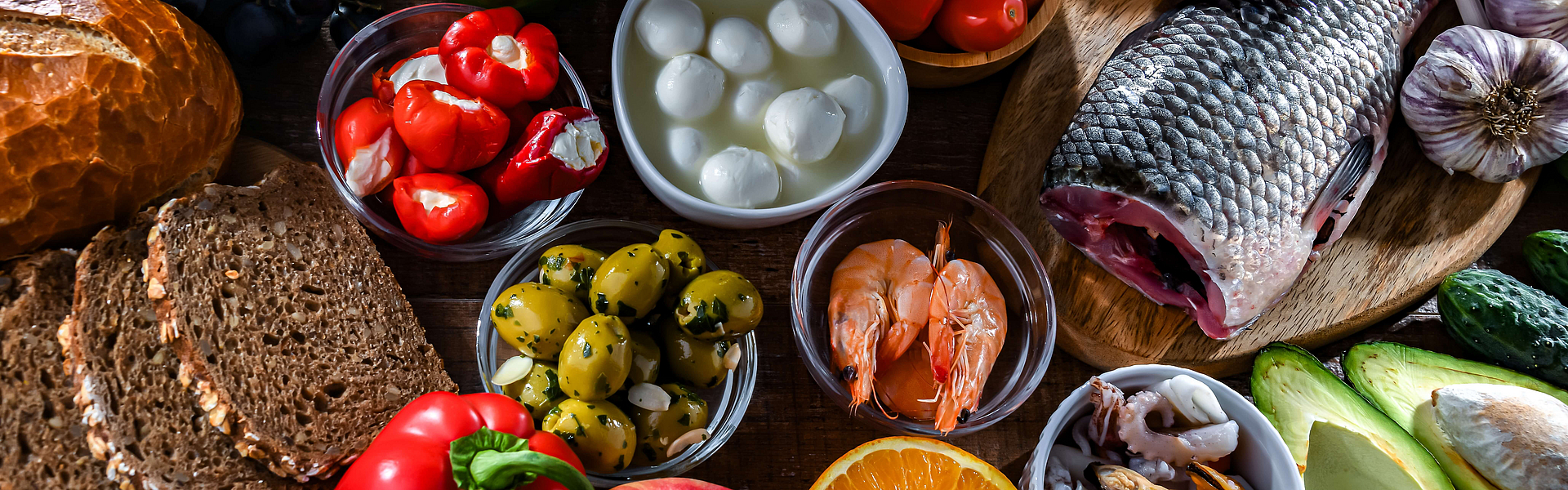 Auswahl an Lebensmitteln einer mediterranen Ernährung zum Beispiel Fisch, Vollkorbrot, Gemüse, Obst