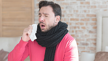 Mann hat einen Schnupfen - er ist krank.