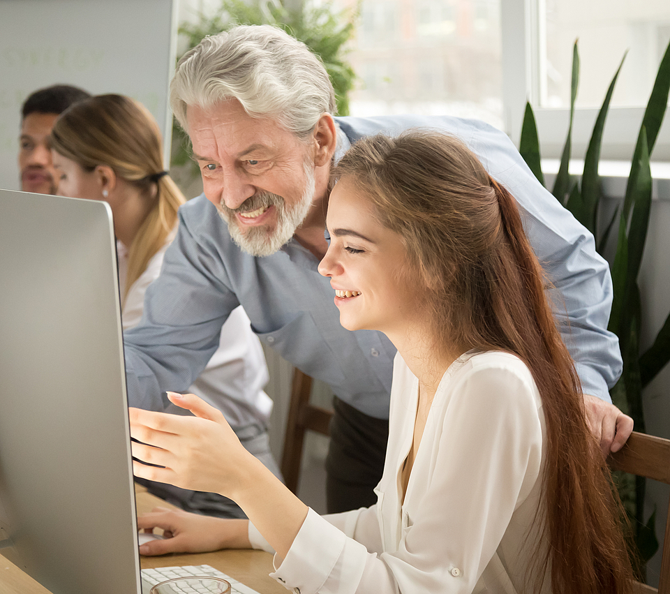 Der Chef zeigt der jungen Angestellten am Laptop wie sie die Neuigkeiten der mhplus Wissensseite für Arbeitgeber aufrufen kann.