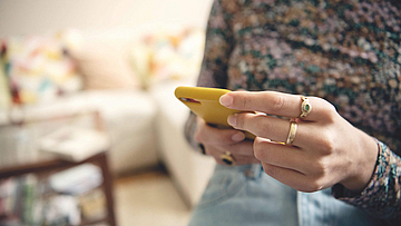 Man sieht nur das Smartphone, eine Frau tippt auf dem Display.