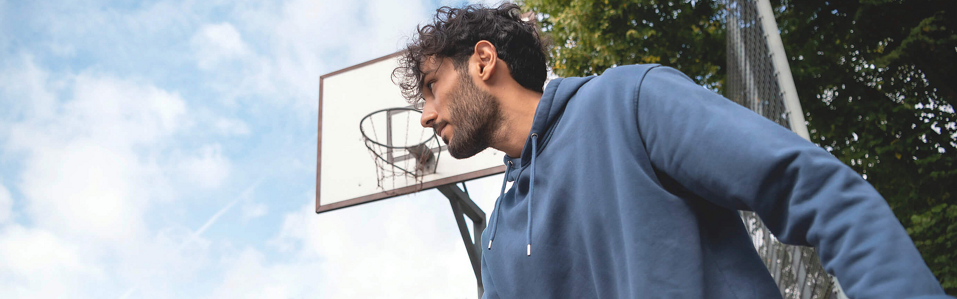 Mann prellt auf dem Sportplatz einen Basketball.