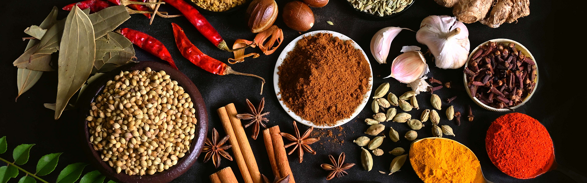 Verschiedene entzündungshemmende Gewürze vor einem dunklen Hintergrund