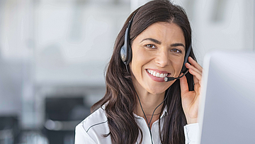 Eine Agentin in eine Callcenter mit einem Headset. Sie lacht.