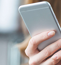 Blonde Frau mit einem Smartphone in der Hand. Man kann nur die Hände und das Smartphone sehen.