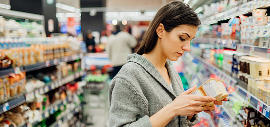 Frau im Supermarkt mit Lebensmittelallergie überprüft die Zutatenliste.