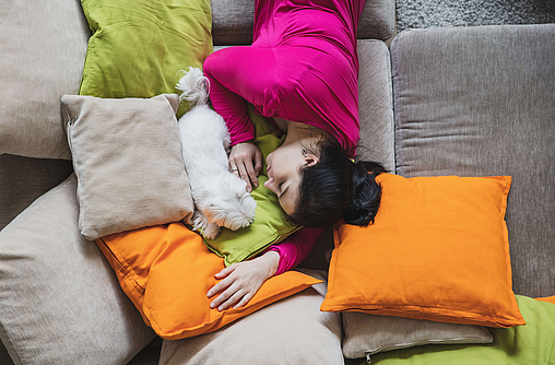 Frau mit unregelmäßigem Schlafrhythmus liegt auf Sofa