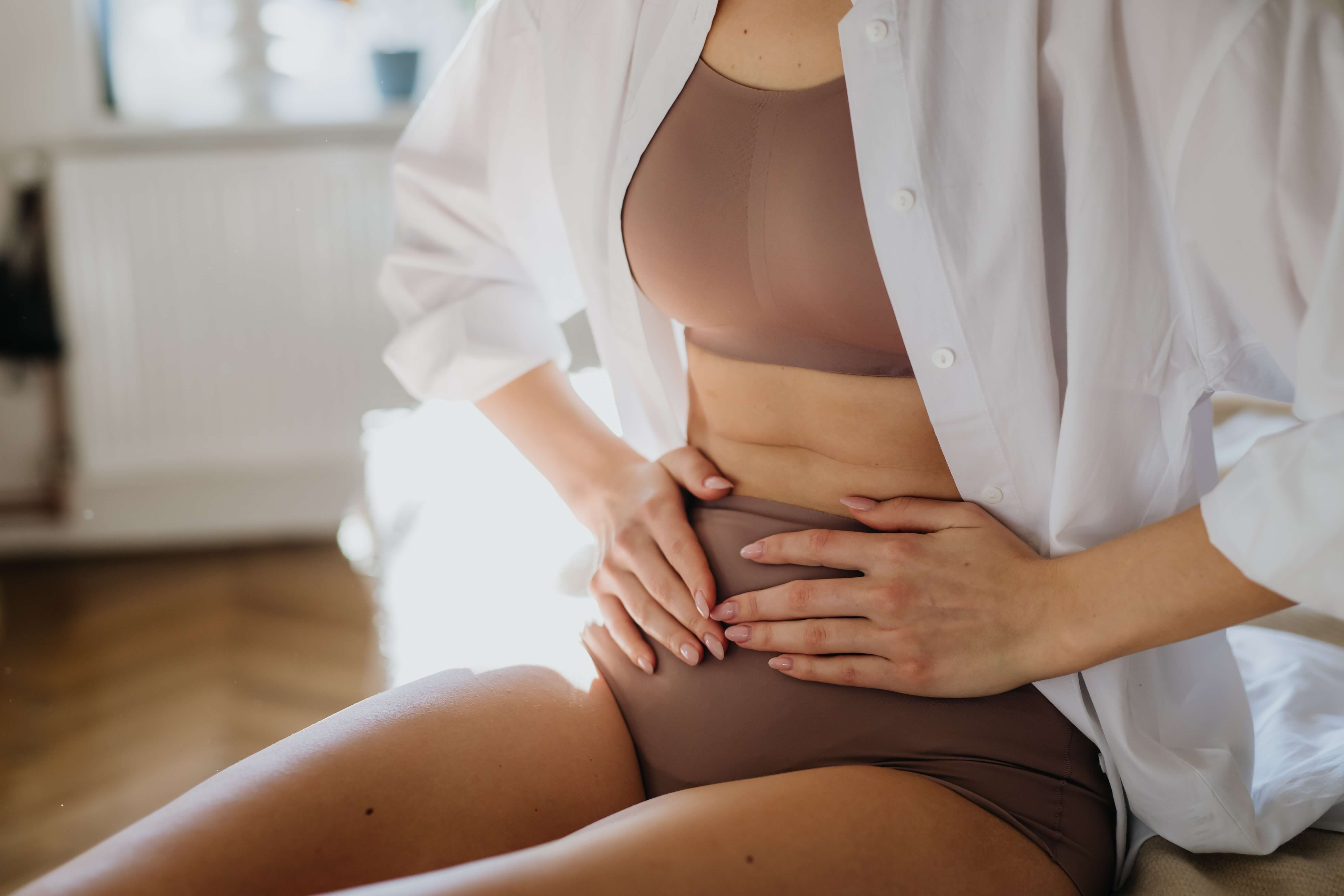 Symbolbild für Endometriose - Frau hält sich vor Schmerzen den Bauch